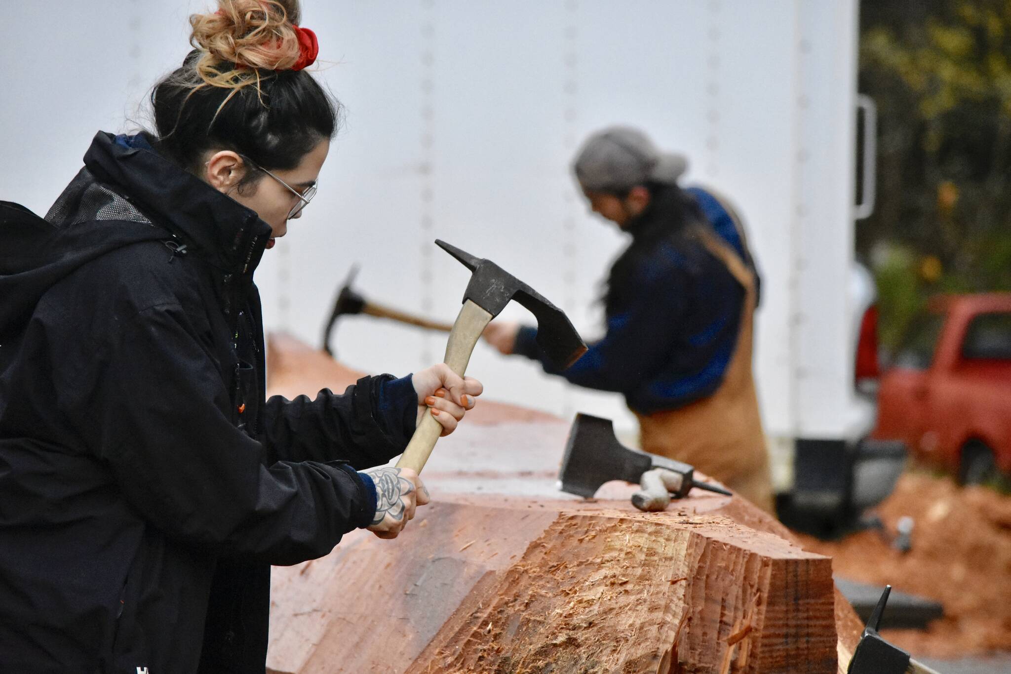 University of Alaska Student Skaydu.û Jules, carves a red cedar log under the supervision of Tlingit master carver Wayne Price in the parking lot of Angoon High School on Tuesday. Jules, a member of the Teslin Tlingit Council, a self-governing First Nation based in Teslin in Southern Yukon Territory, Canada, and said she wants to become a Tlingit language teacher.