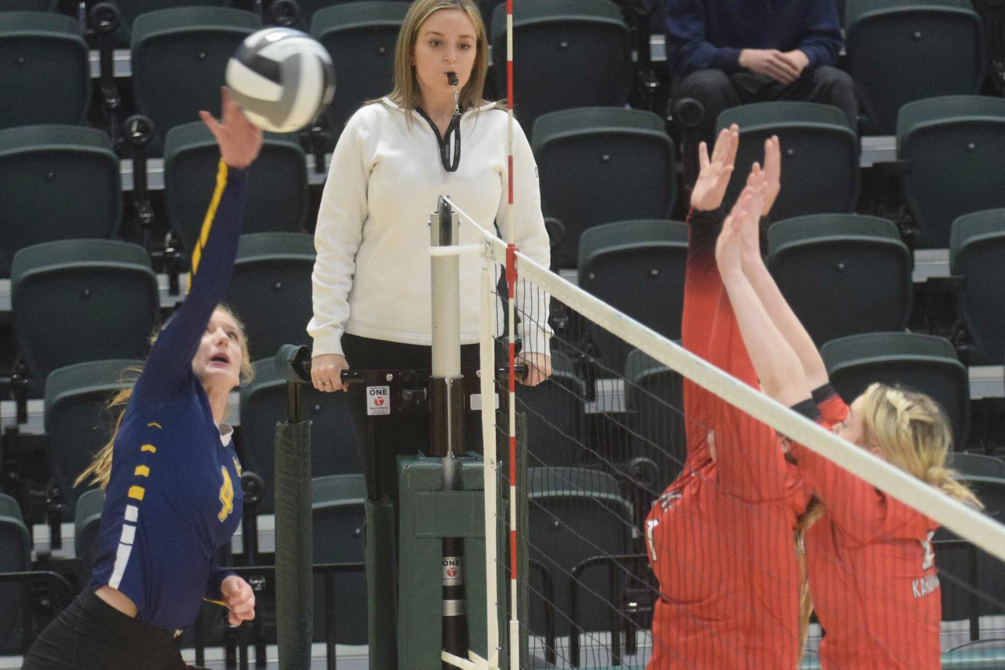 Homer’s Gracie Gummer goes up for a kill against Kenai blockers Calani Holmes and Emma Beck during the 3A state volleyball consolation game at the Alaska Airlines Center in Anchorage, Alaska, on Saturday, Nov. 13, 2021. (Camille Botello/Peninsula Clarion)