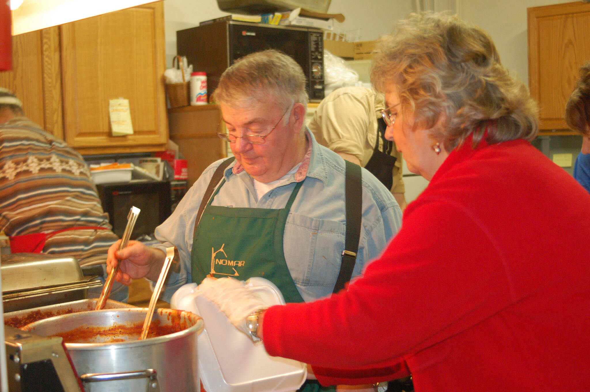 File photo by Michael Armstrong / Homer News
Ben Mitchell, left, serves spaghetti to helper Pat Wells in the kitchen at a past Share the Spirit spaghetti feed.