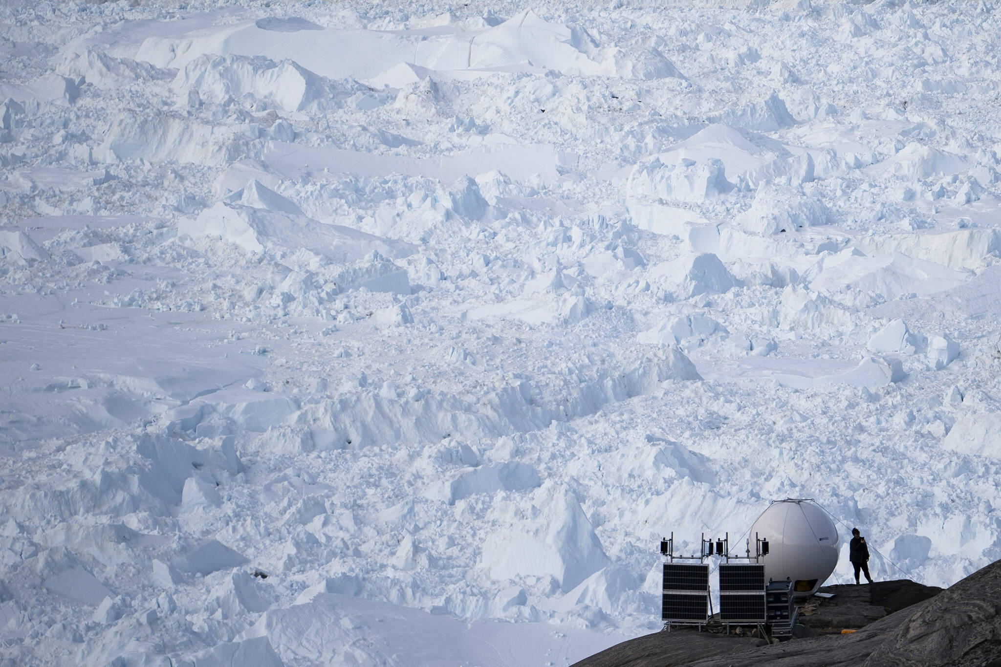 FILE - A woman stands next to an antenna at an NYU base camp at the Helheim glacier in Greenland on Friday, Aug. 16, 2019. In an effort to combat climate change and help develop Arctic communities, the Department of Energy Wednesday announced it was seeking to develop new sustainable energy projects in Alaska. (AP Photo / Felipe Dana)