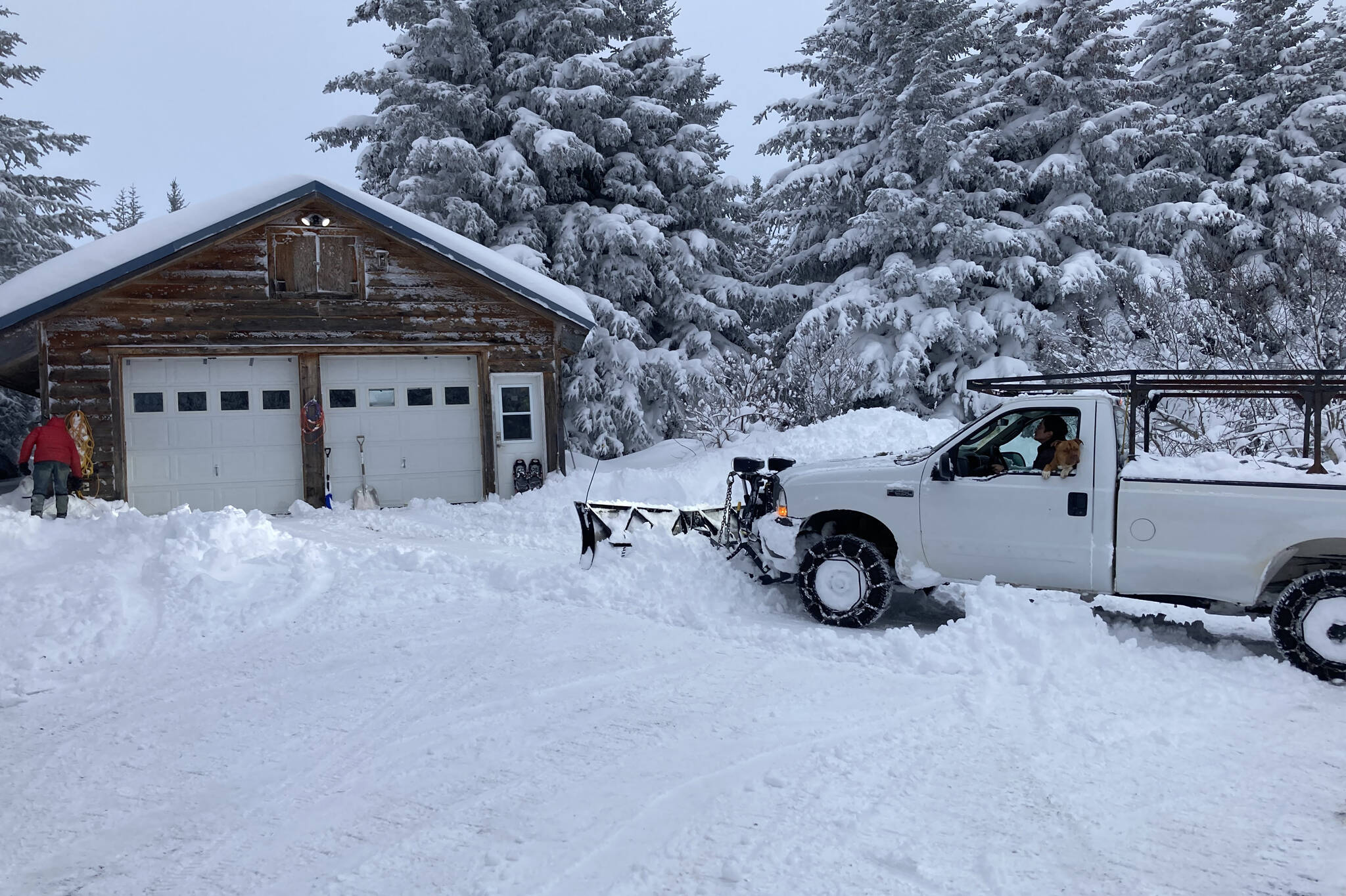 Jim Levine, left, watches as his Diamond Ridge driveway gets plowed on Monday, Nov. 29, 2021, near Homer, Alaska. Over the Thanksgiving Day weekend, some areas of the southern Kenai Peninsula got up to 3 feet of snow. The weekend forecast calls for clear and cold on Friday, with a 70% chance of snow on Sunday, (Photo by Michael Armstrong/Homer News)