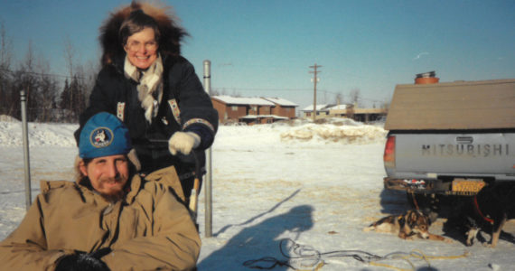 Michael Armstrong, seated, in sled, gives his mother, Sylvia Jander, the unique Alaska experience of driving a sled-dog team in February 1989 in Anchorage, Alaska. (Photo by Jenny Stroyeck)