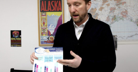 Former Alaska lawmaker Jason Grenn holds an Alaska Division of Elections brochure explaining ranked choice voting at his office in Anchorage, Alaska, on Friday, Jan. 14, 2022. Grenn was sponsor of a ballot initiative passed by Alaska voters in 2020 that would end party primaries and send the top four vote-getters, regardless of party affiliation, to the general election, where ranked-choice voting would determine a consensus winner. The model is unique among states and viewed by supporters as a way to encourage civility and cooperation among elected officials. The Alaska Supreme Court is set to hear arguments over the system Tuesday, Jan. 18, 2022. (AP Photo / Mark Thiessen)