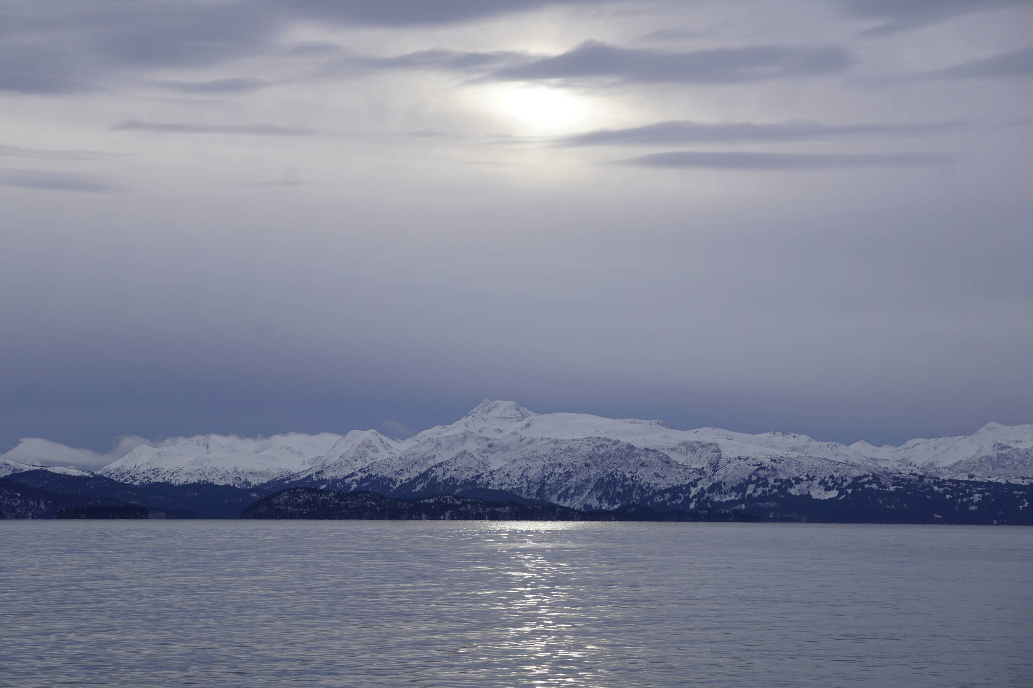 Clouds obscure the sun on Monday, Jan. 18, 2022, as seen from the Mariner Park beach in Homer, Alaska. Yukon Island is in the distance. Almost a month after the winter solstice, the sun rises higher in the sky at mid-day. (Photo by Michael Armstrong/Homer News)