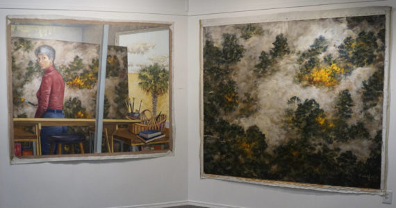 "Selected Works and Sketches by Gaye Wolfe," showing at the Homer Council on the Arts through March, includes these two paintings by Wolfe: a painting of a wildfire, right, and then a self-portrait of Wolfe, left, creating the painting. (Photo by Michael Armstrong/Homer News)