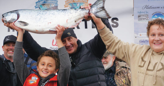 Andrew Marley, the 2021 Homer Winter King Salmon Tournament winner, at left, holds his prize winning 25.62-pound white king salmon on Saturday, April 17, on the Homer Spit in Homer. Helping him are his father, Jay Marley, center, and older brother Weston Marley, right. The family team included Erica Marley, not shown, all fishing on the Fly Dough. (Photo by Michael Armstrong/Homer News)