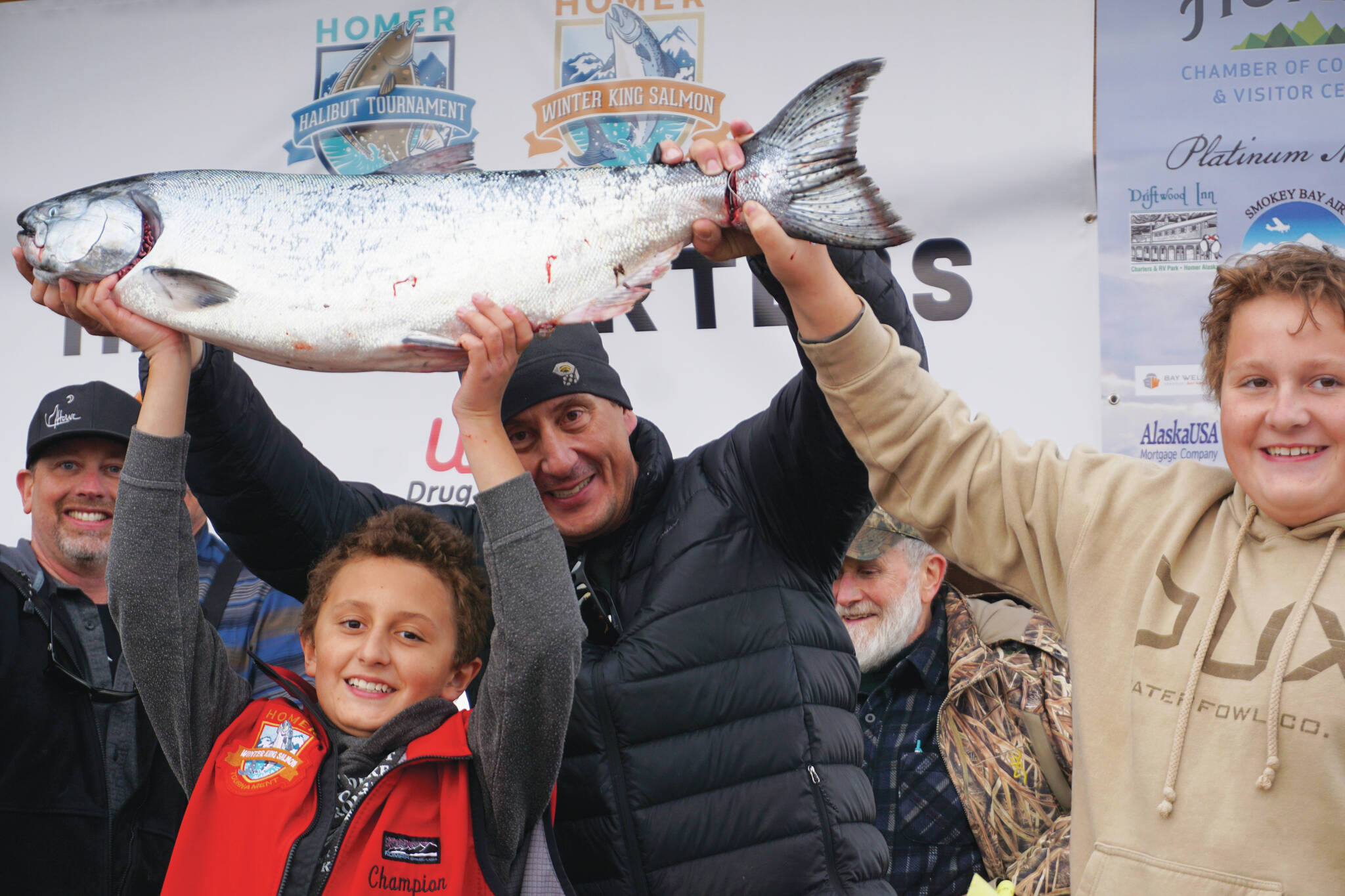 Andrew Marley, the 2021 Homer Winter King Salmon Tournament winner, at left, holds his prize winning 25.62-pound white king salmon on Saturday, April 17, on the Homer Spit in Homer. Helping him are his father, Jay Marley, center, and older brother Weston Marley, right. The family team included Erica Marley, not shown, all fishing on the Fly Dough. (Photo by Michael Armstrong/Homer News)