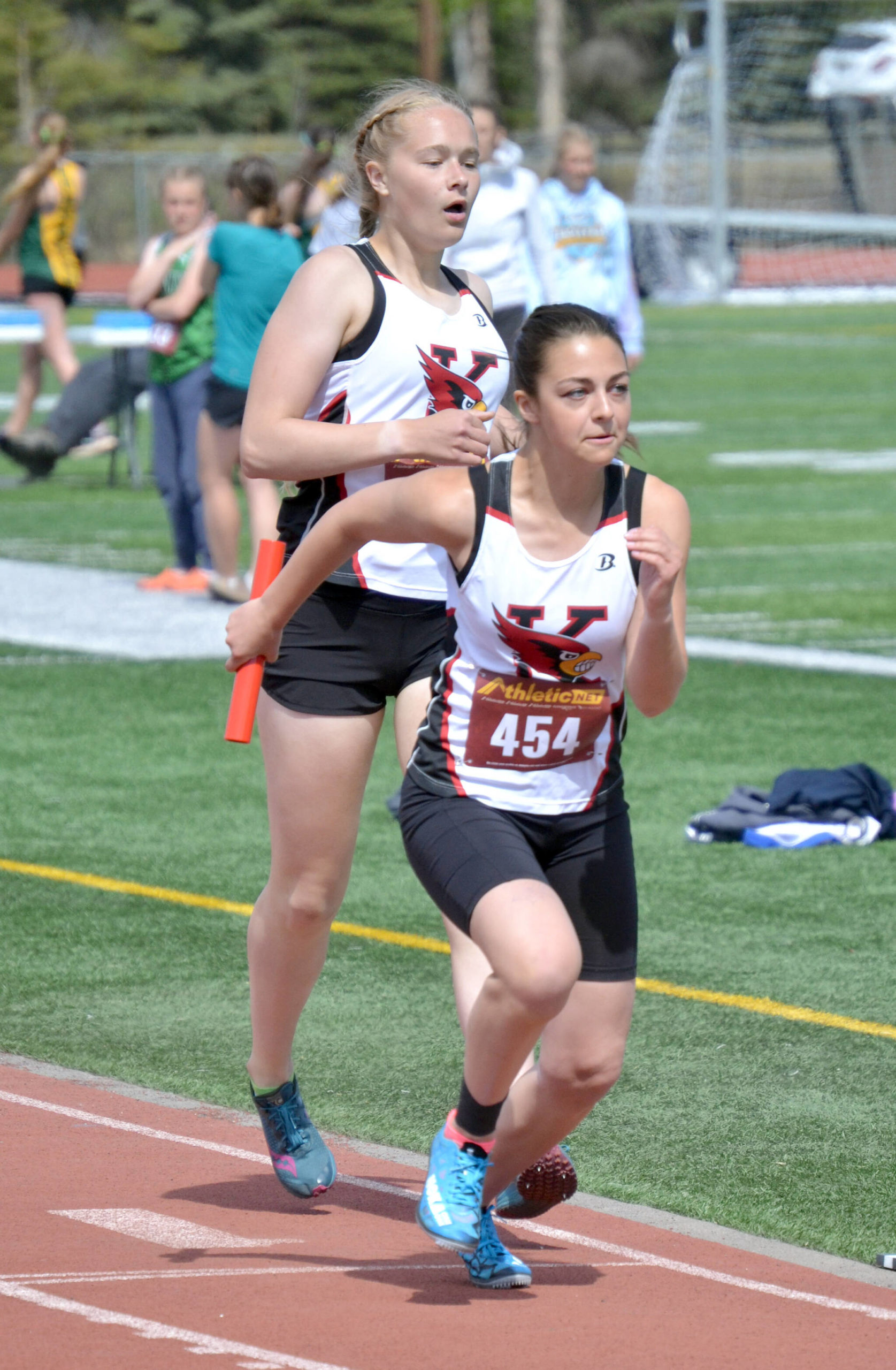Emily Moss hands the baton to Summer Foster on the way to Kenai Central winning the 3,200-meter relay at the Region 3/Division II meet Saturday, May 21, 2022, at Ed Hollier Field at Kenai Central High School in Kenai, Alaska. (Photo by Jeff Helminiak/Peninsula Clarion)