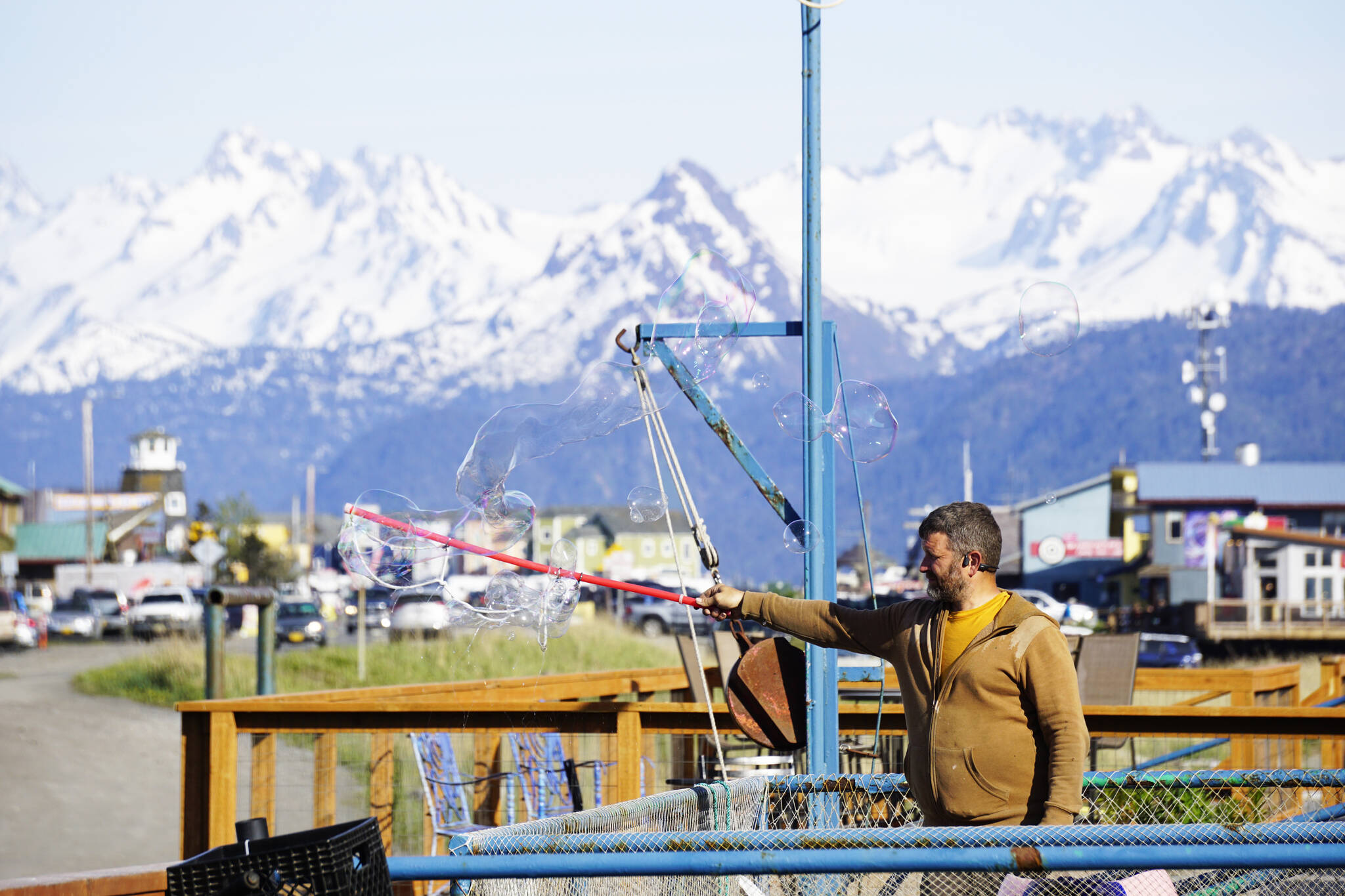 Matthew Stillman forms giant soap bubbles on Thursday, May 26, 2022, at the Homer Shores Boardwalk on the Homer Spit in Homer, Alaska. (Photo by Michael Armstrong/Homer News)