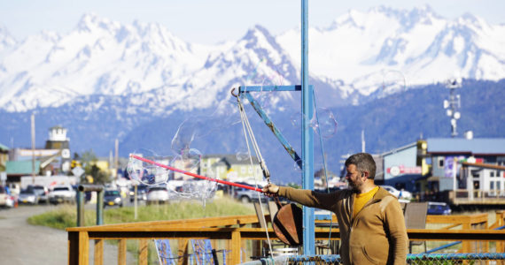 Matthew Stillman forms giant soap bubbles on Thursday, May 26, 2022, at the Homer Shores Boardwalk on the Homer Spit in Homer, Alaska. (Photo by Michael Armstrong/Homer News)