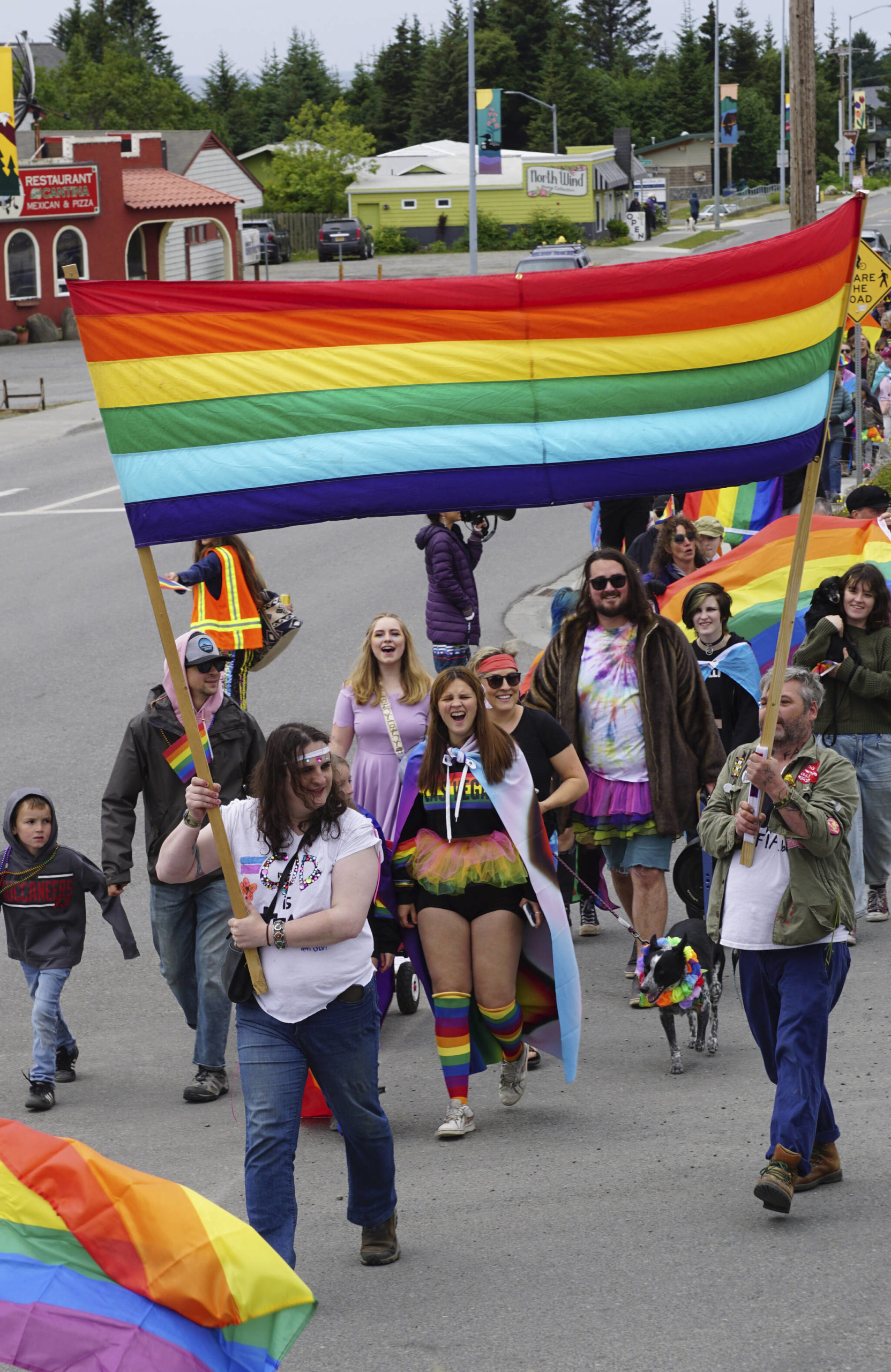 People holding a Pride banner lead the Pride-X-Juneteenth parade on Saturday, June 18, 2022, on Pioneer Avenue in Homer, Alaska. (Photo by Michael Armstrong/Homer News)