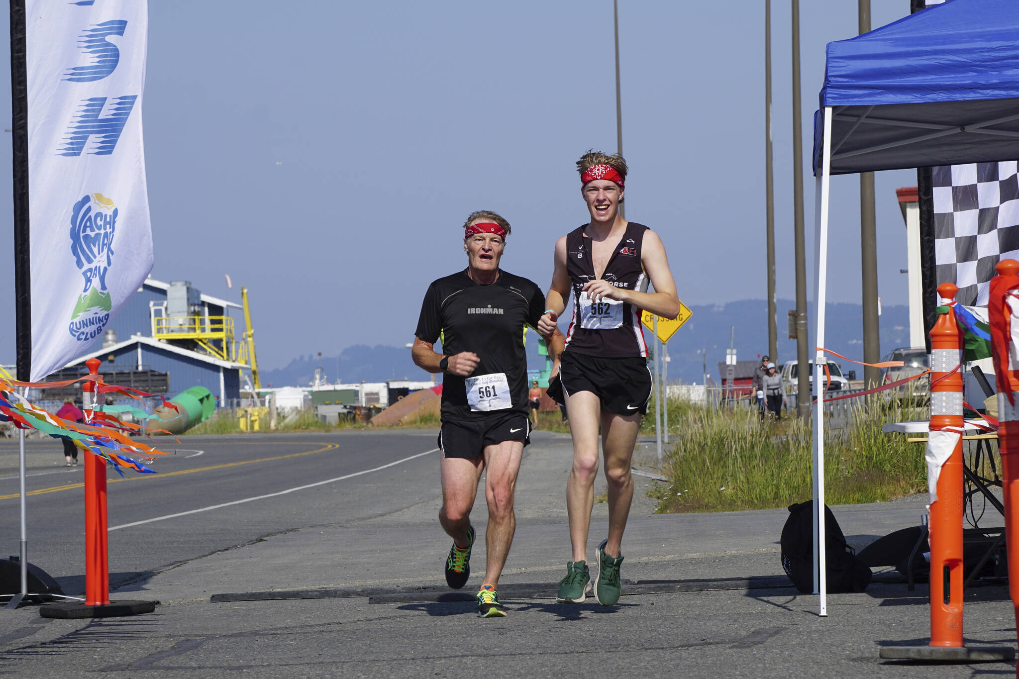 Shaun Marshall-Pryde, left, and Stirling Marshall-Pryde, right, finish together the 2022 Homer Spit Run, on Saturday, June 25, 2022, at the End of the Road Park in Homer, Alaska. (Photo by Michael Armstrong/Homer News)