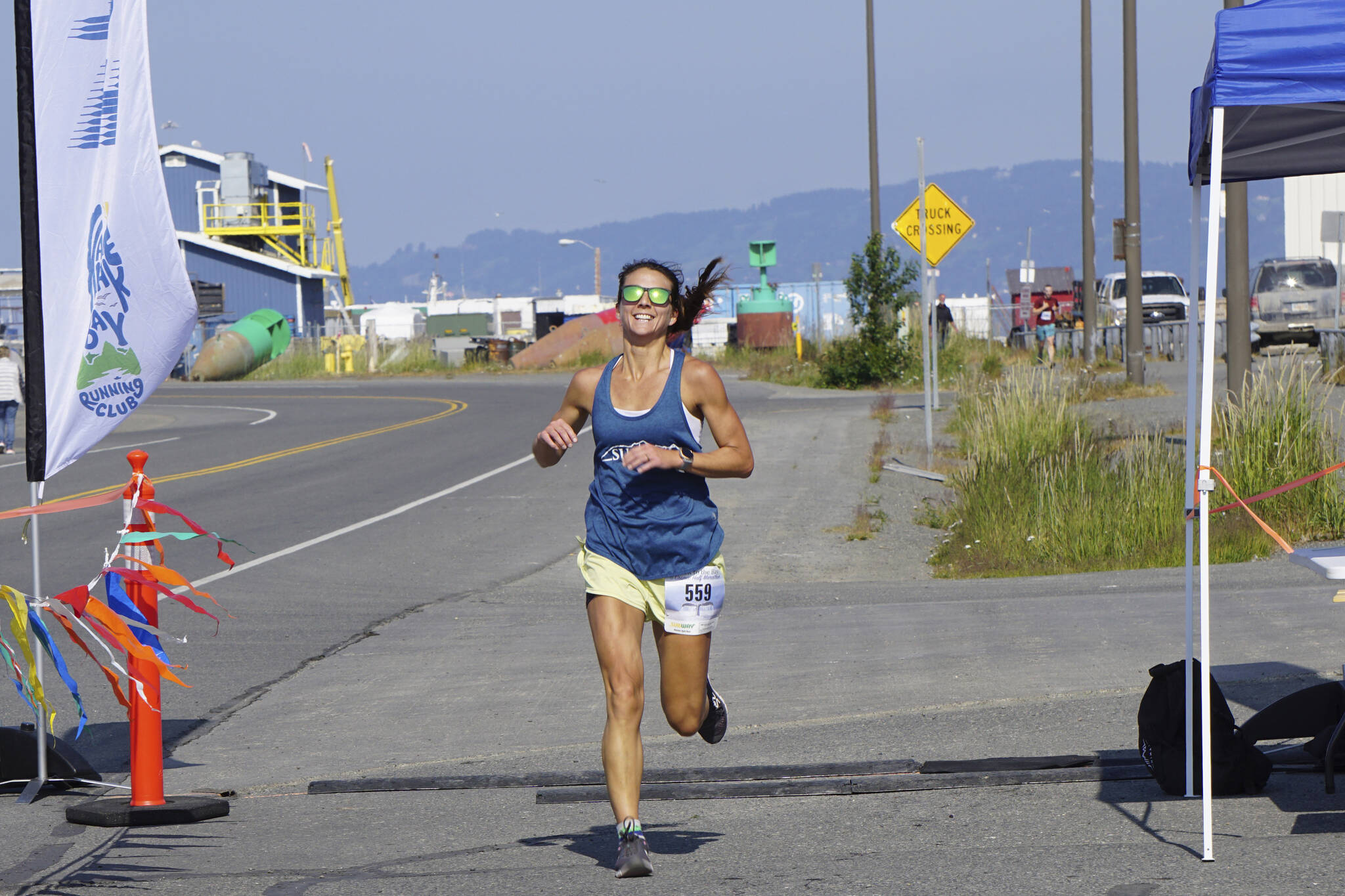 Amanda Cherok, the first-place woman runner in the 2022 Homer Spit Run, crosses the finish line on Saturday, June 25, 2022, at the End of the Road Park in Homer, Alaska. (Photo by Michael Armstrong/Homer News)
