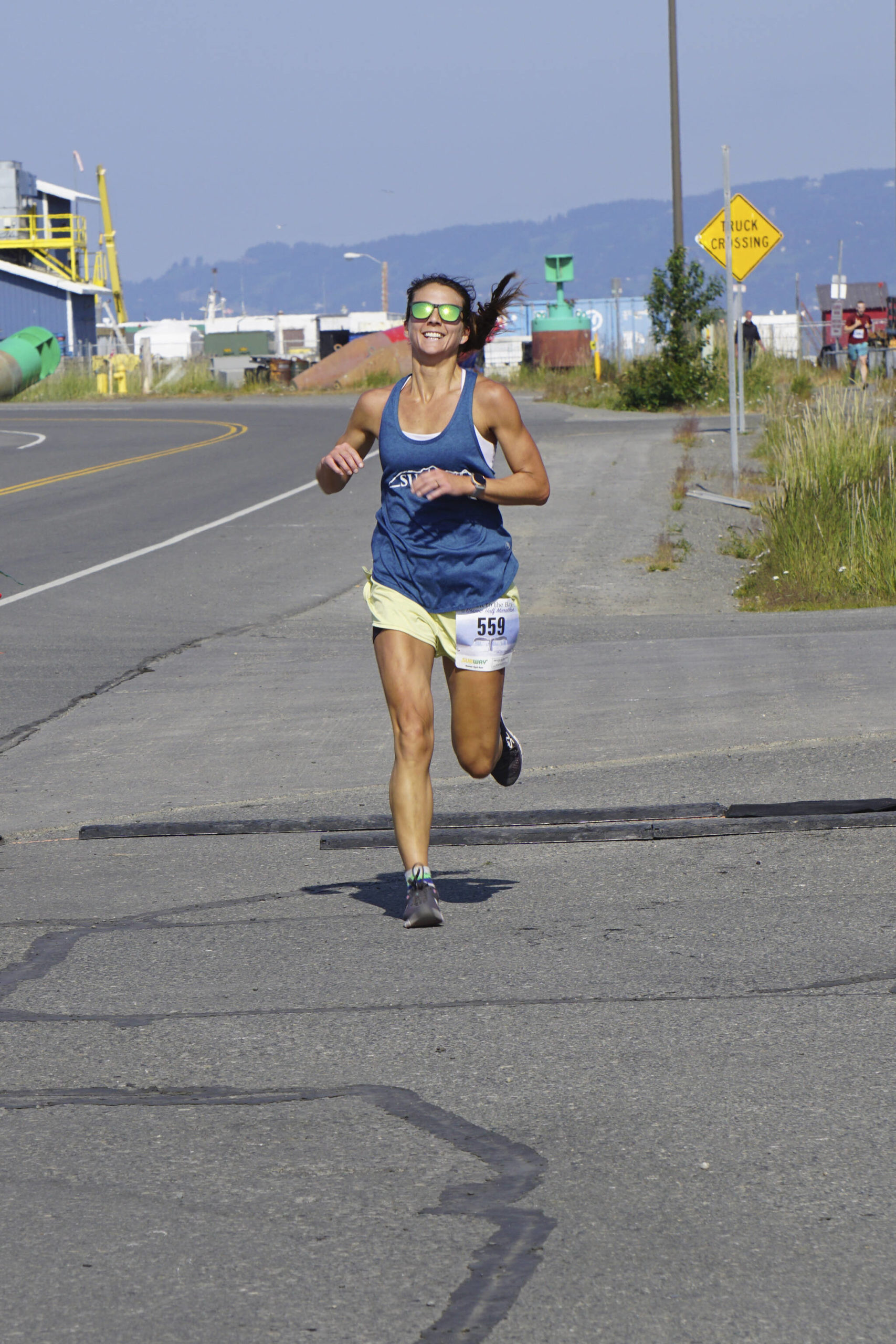 Amanda Cherok, the first-place woman runner in the 2022 Homer Spit Run, crosses the finish line on Saturday, June 25, 2022, at the End of the Road Park in Homer, Alaska. (Photo by Michael Armstrong/Homer News)