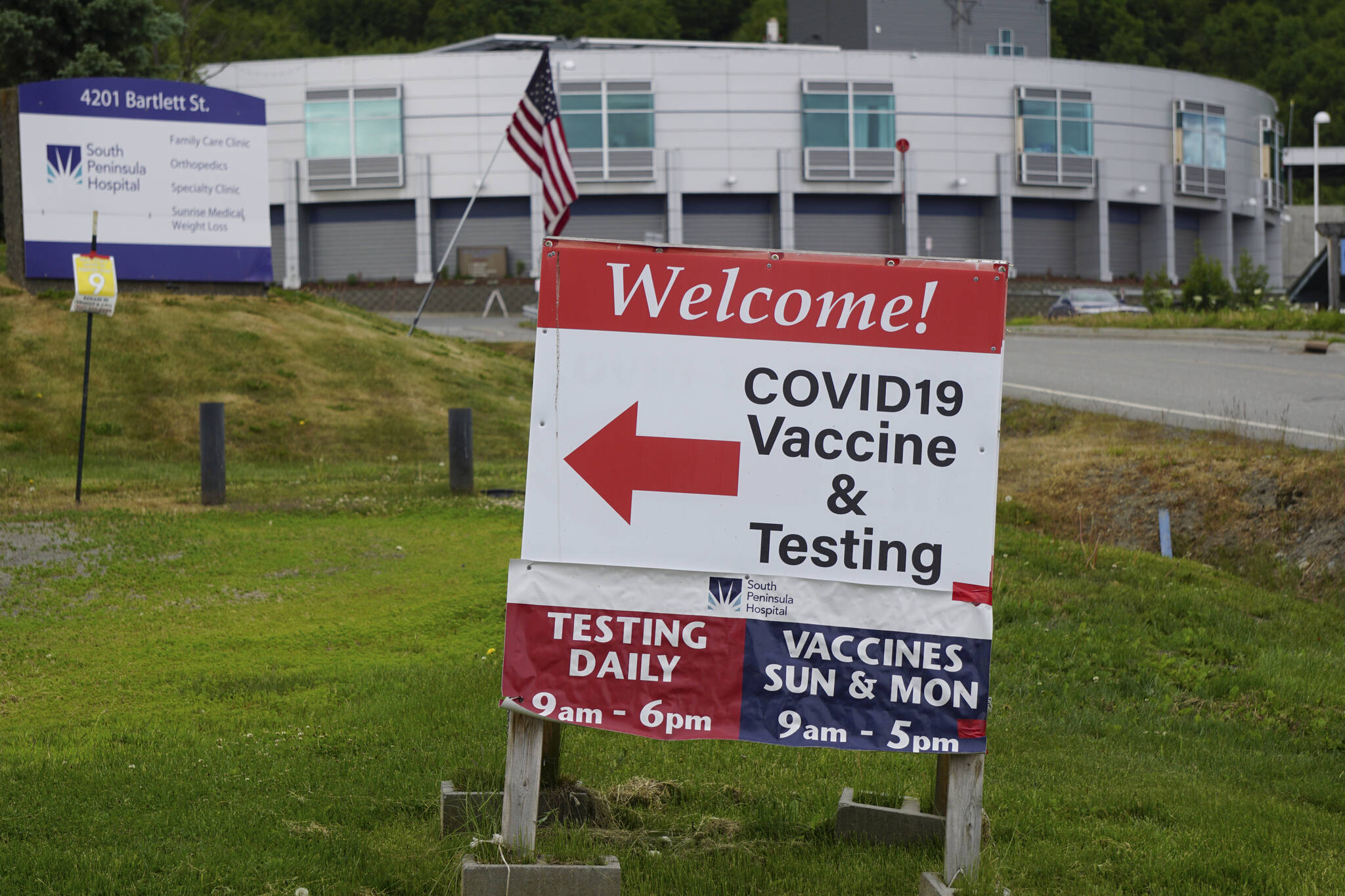 A sign points the way to the South Peninsula Hospital COIVD-19 testing and vaccine clinic at 4201 Bartlett Street on Flag Day, Tuesday, June 14, 2022, in Homer, Alaska. (Photo by Michael Armstrong/Homer News)