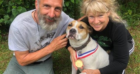 Greg and Teresa Groeneweg pose with their dog, Ace, who is wearing a lifesaver medal Greg received from the Anchorage Fire Department years ago. He said Ace deserves it now more than him, for fighting off a bear. (Courtesy Greg Groeneweg)