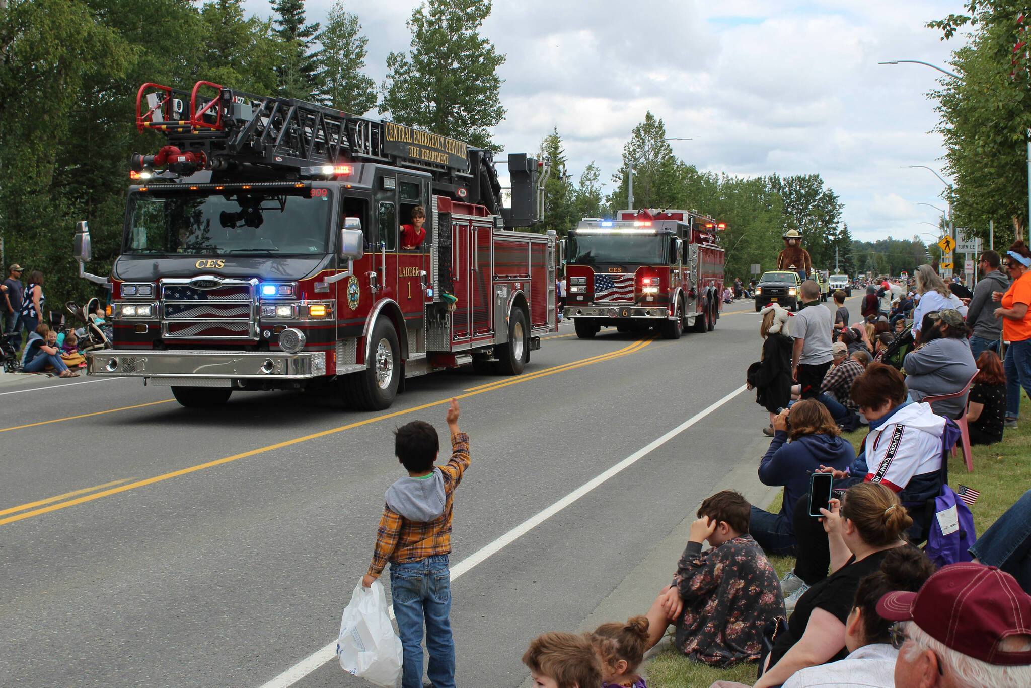 Attendees wave to Central Emergency Services fire trucks during the 65th annual Soldotna Progress Days Parade on Saturday, July 23, 2022, in Soldotna, Alaska. (Ashlyn O’Hara/Peninsula Clarion)