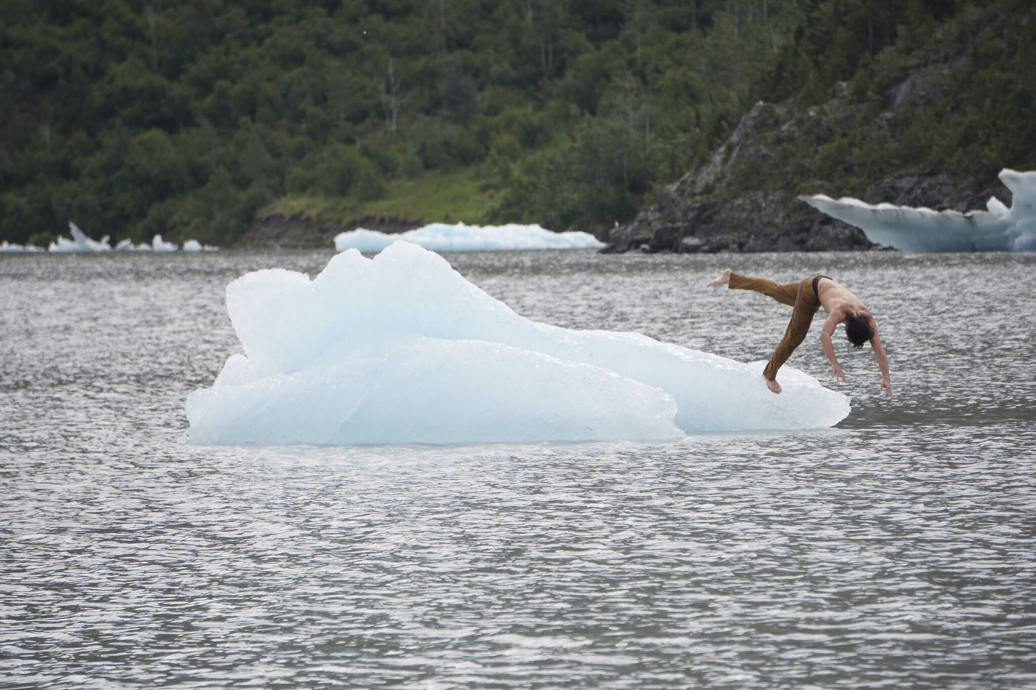A man dives off an iceberg in Grewingk Glacier Lake on Monday, July 25, 2022, in Kachemak Bay State Park near Halibut Cove, Alaska. (Photo by Michael Armstrong/Homer News)