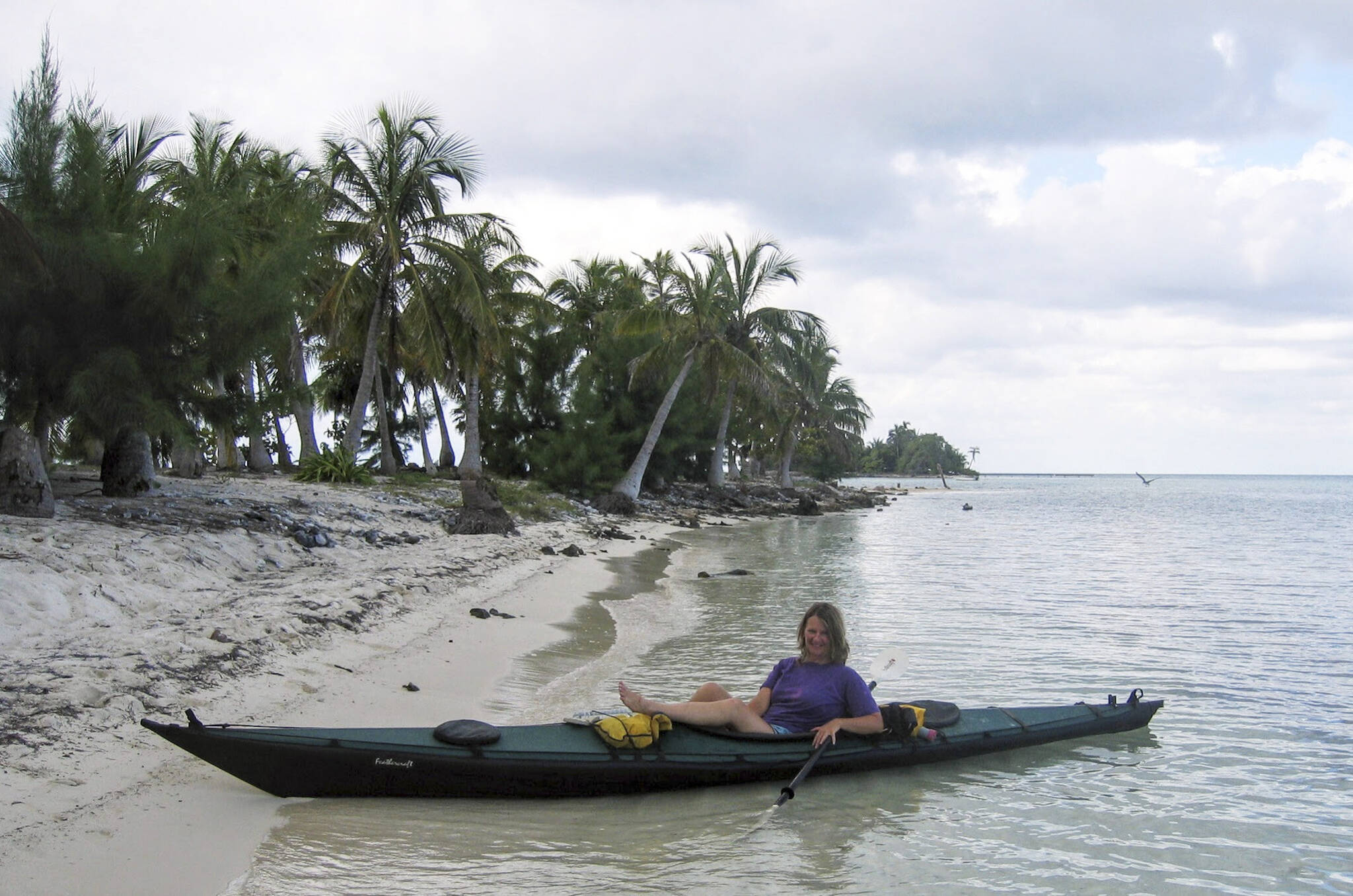 Susan Aramovich relaxes in her kayak on a tropical beach in this photo from Scott Burbank’s “Interior Waypoints.” (Photo provided)