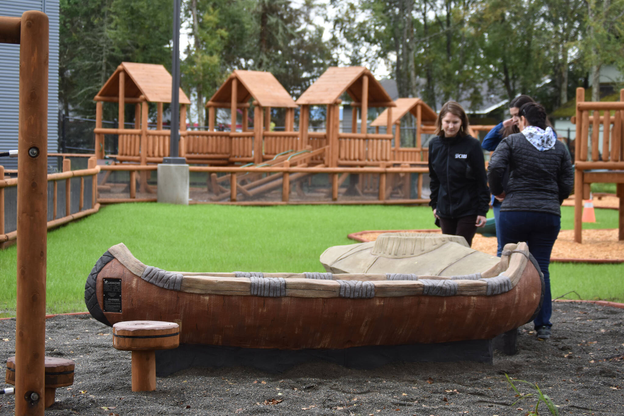 Members of a tour at the Kahtnuht’ana Duhdeldiht Campus check out the birch bark canoe and kayak on the playground on Thursday, Sept. 1, 2022, in Kenai, Alaska. (Jake Dye/Peninsula Clarion)