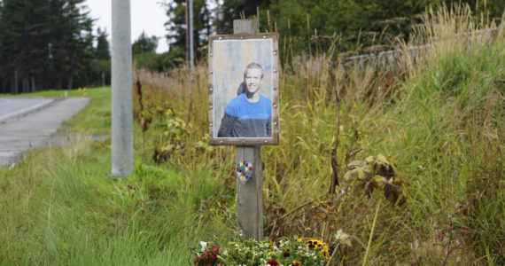 A memorial for Drew Brown with his photo, flowers and a heart sculpture was installed at the site where he died in a car crash on the Sterling Highway, as seen here on Friday, Sept. 16, 2022, in Homer, Alaska. (Photo by Michael Armstrong/Homer News)