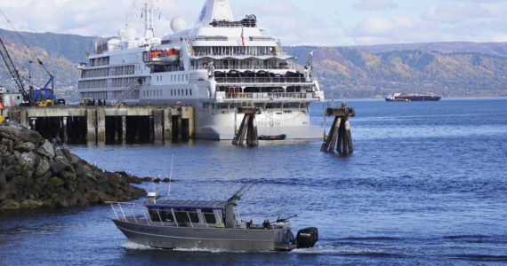 A fishing boat passes the Silversea cruise ship Silver Wind as the boat enters the Homer Harbor on Sunday, Sept. 25, 2022, in Homer, Alaska. (Photo by Michael Armstrong/Homer News)