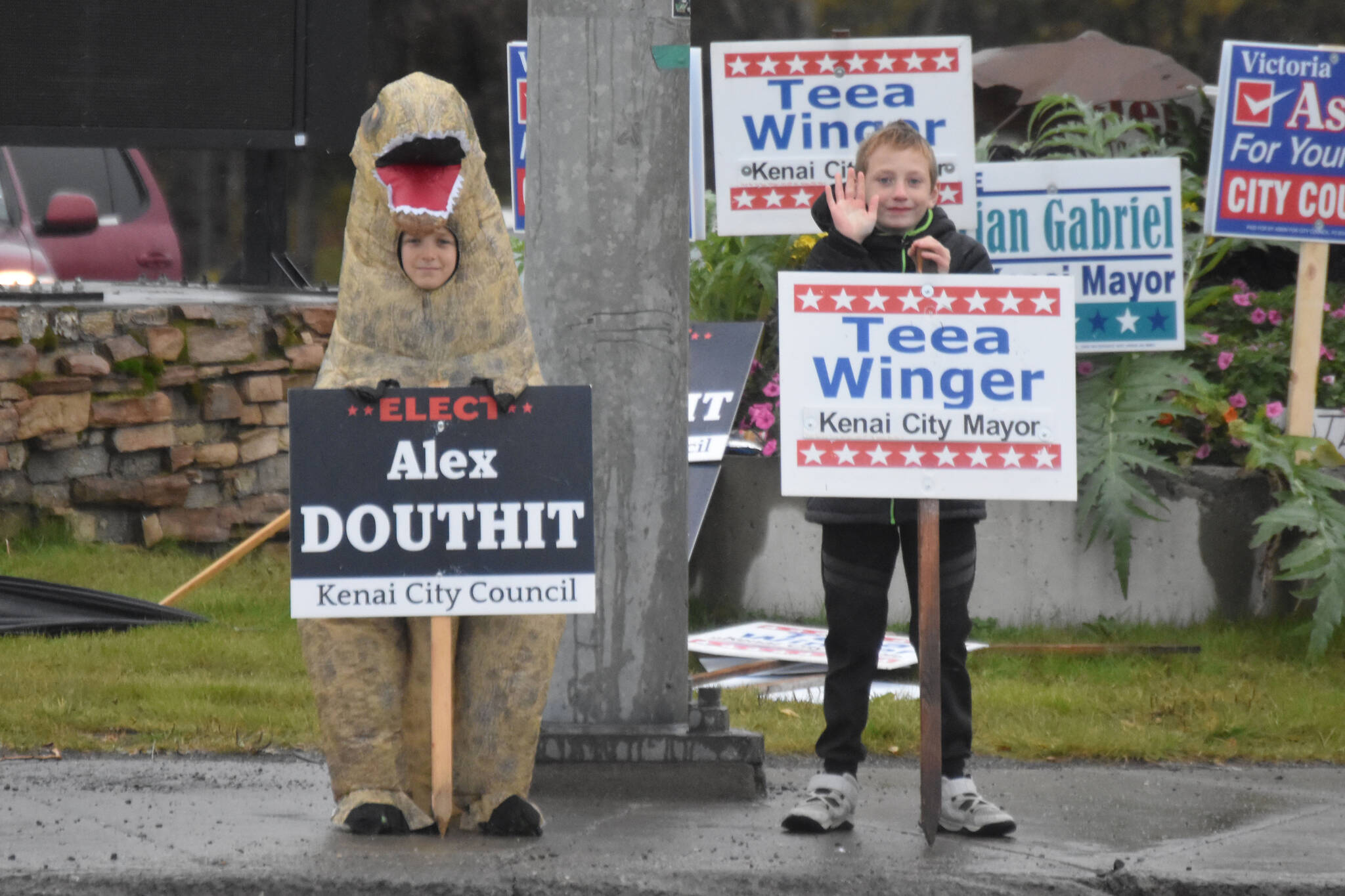 Two kids wave signs for candidates Alex Douthit and Teea Winger on Election Day, Oct. 4, 2022, in Kenai, Alaska. (Jake Dye/Peninsula Clarion)