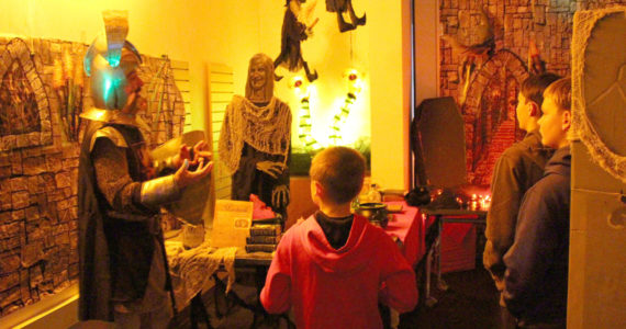 Sir James Adcox, left, leads Silas Barnes, Manoah Barnes and Nehemiah Barnes through the Literary Haunted House at the Kenai Community Library on Oct. 30, 2019. (Photo by Brian Mazurek/Peninsula Clarion)