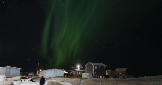 The northern lights appear over Shishmaref, Alaska, Sunday, Oct. 2, 2022. Rising sea levels, flooding, increased erosion and loss of protective sea ice and land have led residents of this island community to vote twice to relocate. But more than six years after the last vote, Shishmaref remains in the same place because the relocation is too costly. (AP Photo/Jae C. Hong)