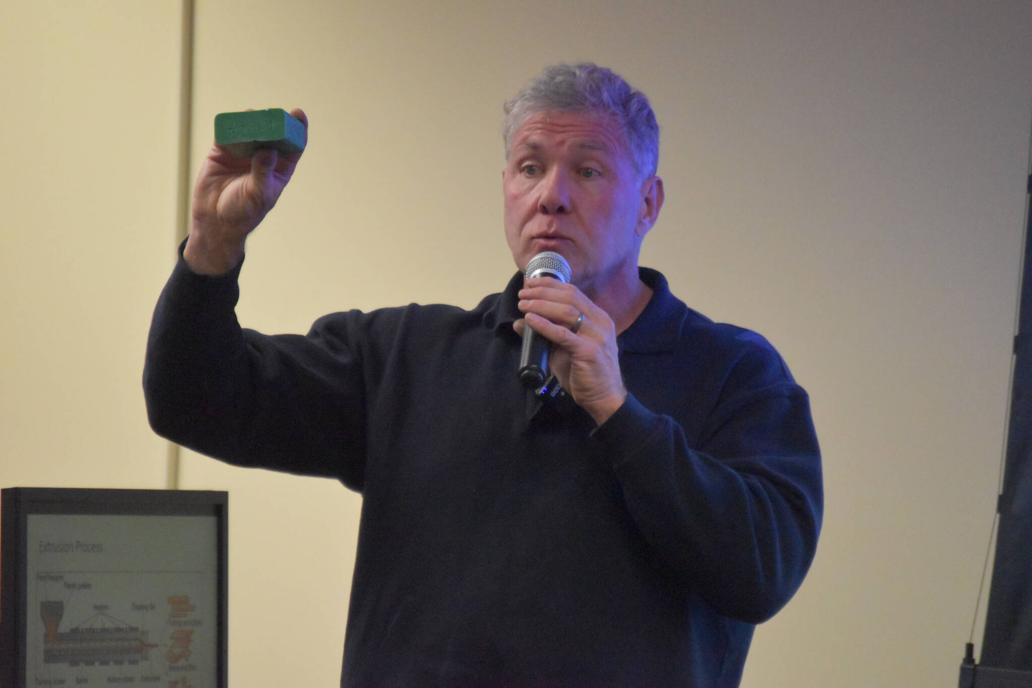 Patrick Simpson speaks about his recycled plastic lumber project while holding a sample of the finished product at a Kenai Peninsula College Showcase on Thursday, Oct. 27, 2022 in Soldotna, Alaska. (Jake Dye/Peninsula Clarion)