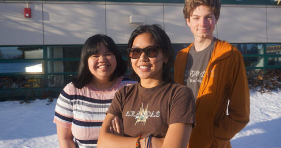 Steller Secondary School seniors gather in the sunshine outside their school on Oct. 27. From left are Pauline Mallari, Samantha Antonio and Zane Barber, all bound for college. They all enjoy the Alaska outdoors lifestyle, but they all expressed lack of confidence in Alaska as a place for young people to build careers. Demographic data shows that young adults are leaving Alaska, contributing to nine straight years of net outmigration. (Photo by Yereth Rosen/Alaska Beacon)