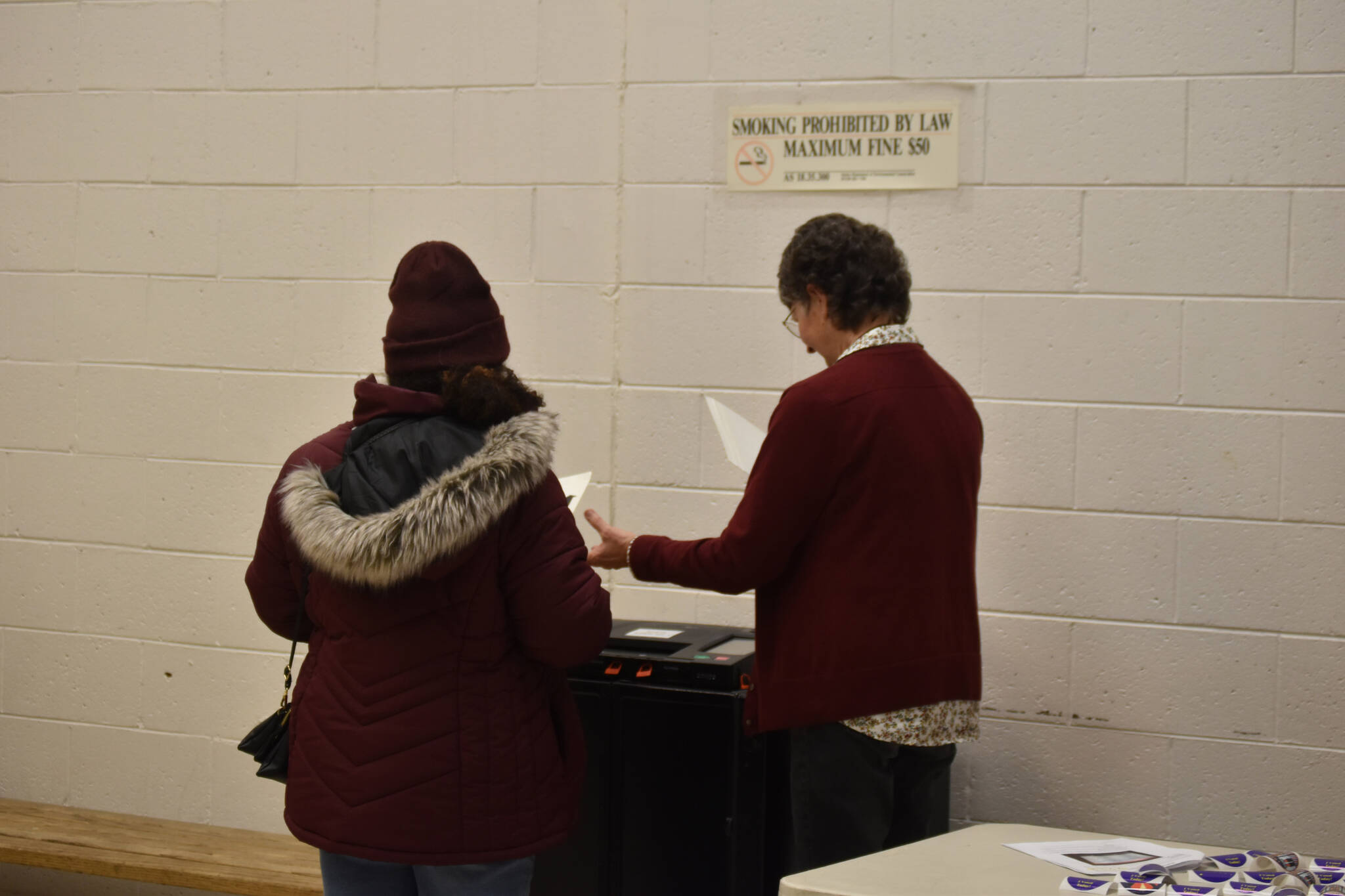 Poll worker Joan Seaman helps a voter to submit their ballot at the Kenai Mall in Kenai, Alaska on Election Day, Nov. 8, 2022. (Jake Dye/Peninsula Clarion)