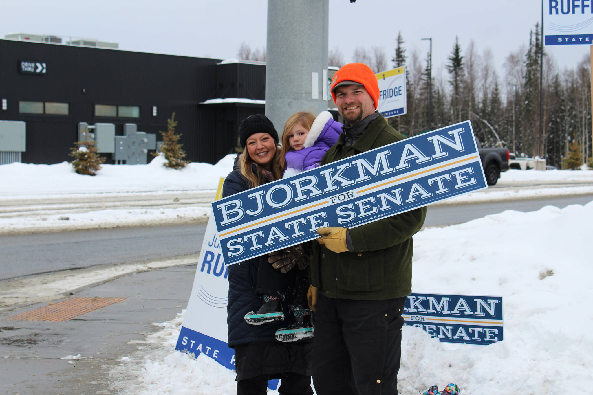 From left, Jamie, Brinna and Jesse Bjorkman wave signs supporting Jesse Bjorkman's bid for Alaska State Senate at the intersection of the Kenai Spur and Sterling highways on Tuesday, Nov. 8, 2022 in Soldotna, Alaska. (Ashlyn O'Hara/Peninsula Clarion)