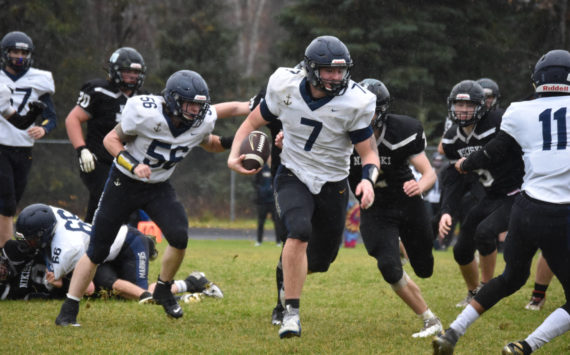 Homer's Carter Tennison runs with the ball, pursued by several Bulldogs, during the playoff game on Saturday, Oct. 8, 2022, at Nikiski Middle/High School in Nikiski, Alaska. (Jake Dye/Peninsula Clarion)