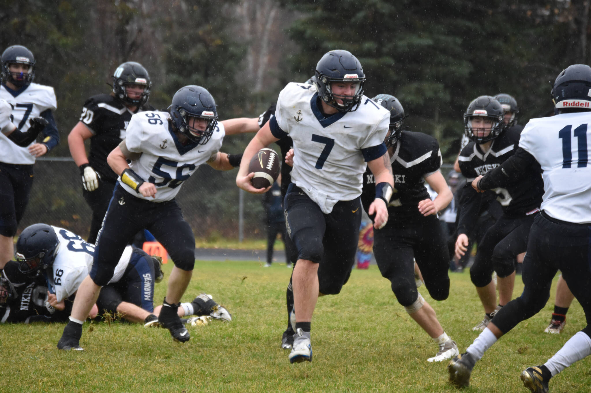 Homer's Carter Tennison runs with the ball, pursued by several Bulldogs, during the playoff game on Saturday, Oct. 8, 2022, at Nikiski Middle/High School in Nikiski, Alaska. (Jake Dye/Peninsula Clarion)