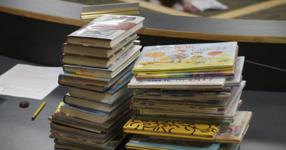Some of the Homer Public Library books a citizens group has asked be removed from the children's section lie on a table at the meeting of the Library Advisory Board on Nov. 15, 2022, in the Cowles Council Chambers at Homer City Hall in Homer, Alaska. (Photo by Michael Armstrong/Homer News)