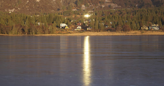 Sun reflected in windows on a house shines on the ice of Beluga Lake on Monday, Nov. 14, 2022, in Homer, Alaska. (Photo by Michael Armstrong/Homer News)