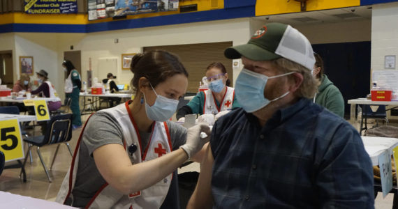 Anna Lewald, left, a registered nurse at South Peninsula Hospital, gives Dave Aplin, right, an influenza vaccine at a flu and Pfizer COVID-19 vaccine clinic Friday, Oct. 15, 2021, at Homer High School in Homer, Alaska. (Photo by Michael Armstrong/Homer News)