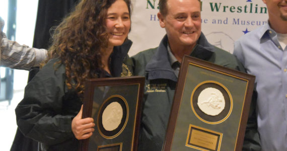 Tela O’Donnell-Bacher and Neldon Gardner hold their plaques after being inducted into the National Wrestling Hall of Fame following a duel wrestling meet on Tuesday, Nov. 22, 2022, at Soldotna High School in Soldotna, Alaska. (Jake Dye/Peninsula Clarion)
