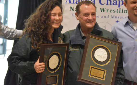Tela O’Donnell-Bacher and Neldon Gardner hold their plaques after being inducted into the National Wrestling Hall of Fame following a duel wrestling meet on Tuesday, Nov. 22, 2022, at Soldotna High School in Soldotna, Alaska. (Jake Dye/Peninsula Clarion)