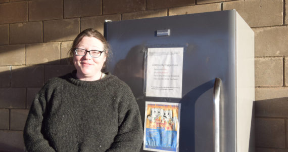 Laura McBride, Food Pantry Coordinator, stands in front of the Community Fridge located at the Homer United Methodist Church on Thursday, Dec. 1 in Homer. (Photo by Charlie Menke / Homer News)