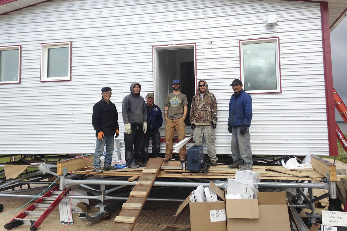 Aaron Cooke, in the T-shirt, poses in front of an efficient house he helped design after he and Newtok residents built it at the new village site of Mertarvik, Alaska, in 2016. (Molly Rettig/Submitted)