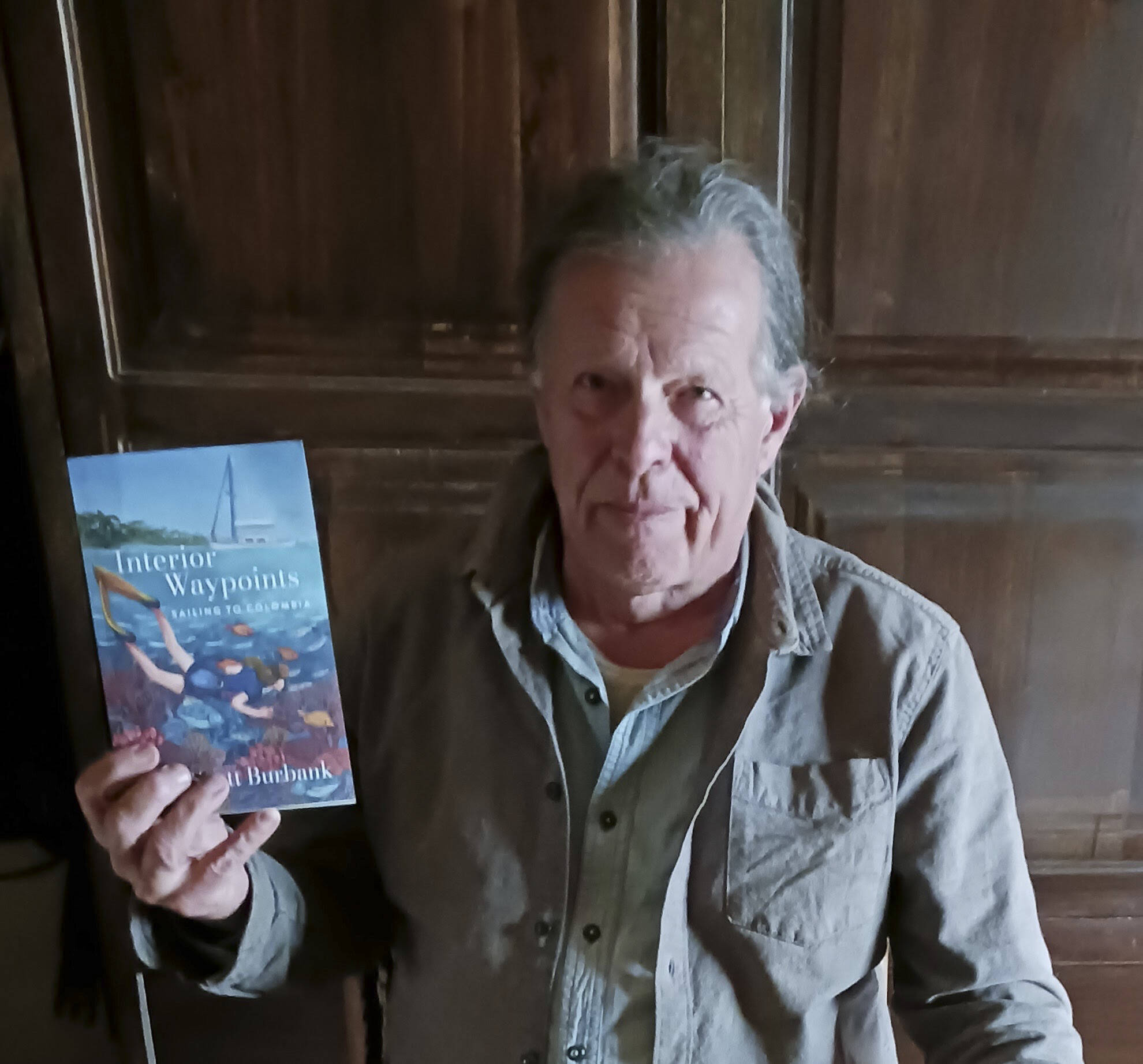 Scott Burbank hold a copy of his adventure book, “Interior Waypoints.” (Photo provided)