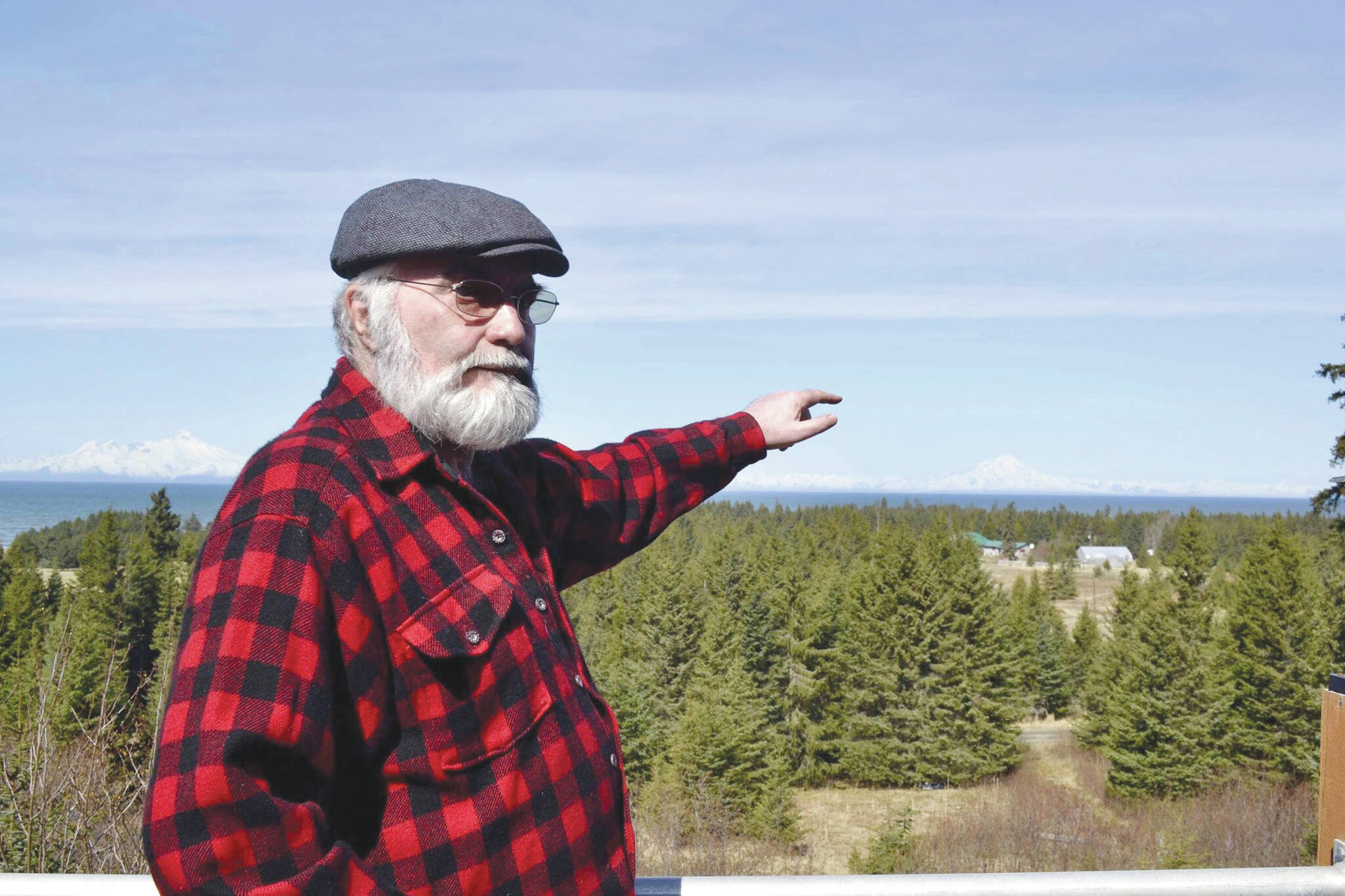 Pete Kineen, a neighbor of the proposed Beachcomber LLC gravel pit, stands on his deck and points to where the pit could be, on May 2, 2019, in Anchor Point, Alaska. (Photo by Victoria Petersen/Peninsula Clarion)
