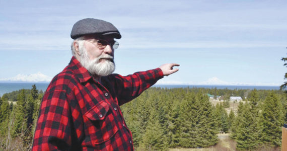 Photo by Victoria Petersen/Peninsula Clarion 
Pete Kineen, a neighbor of the proposed Beachcomber LLC gravel pit, stands on his deck and points to where the pit could be, on May 2, 2019, in Anchor Point, Alaska.