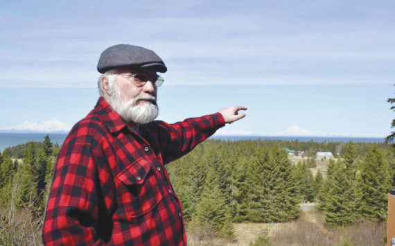 Photo by Victoria Petersen/Peninsula Clarion 
Pete Kineen, a neighbor of the proposed Beachcomber LLC gravel pit, stands on his deck and points to where the pit could be, on May 2, 2019, in Anchor Point, Alaska.