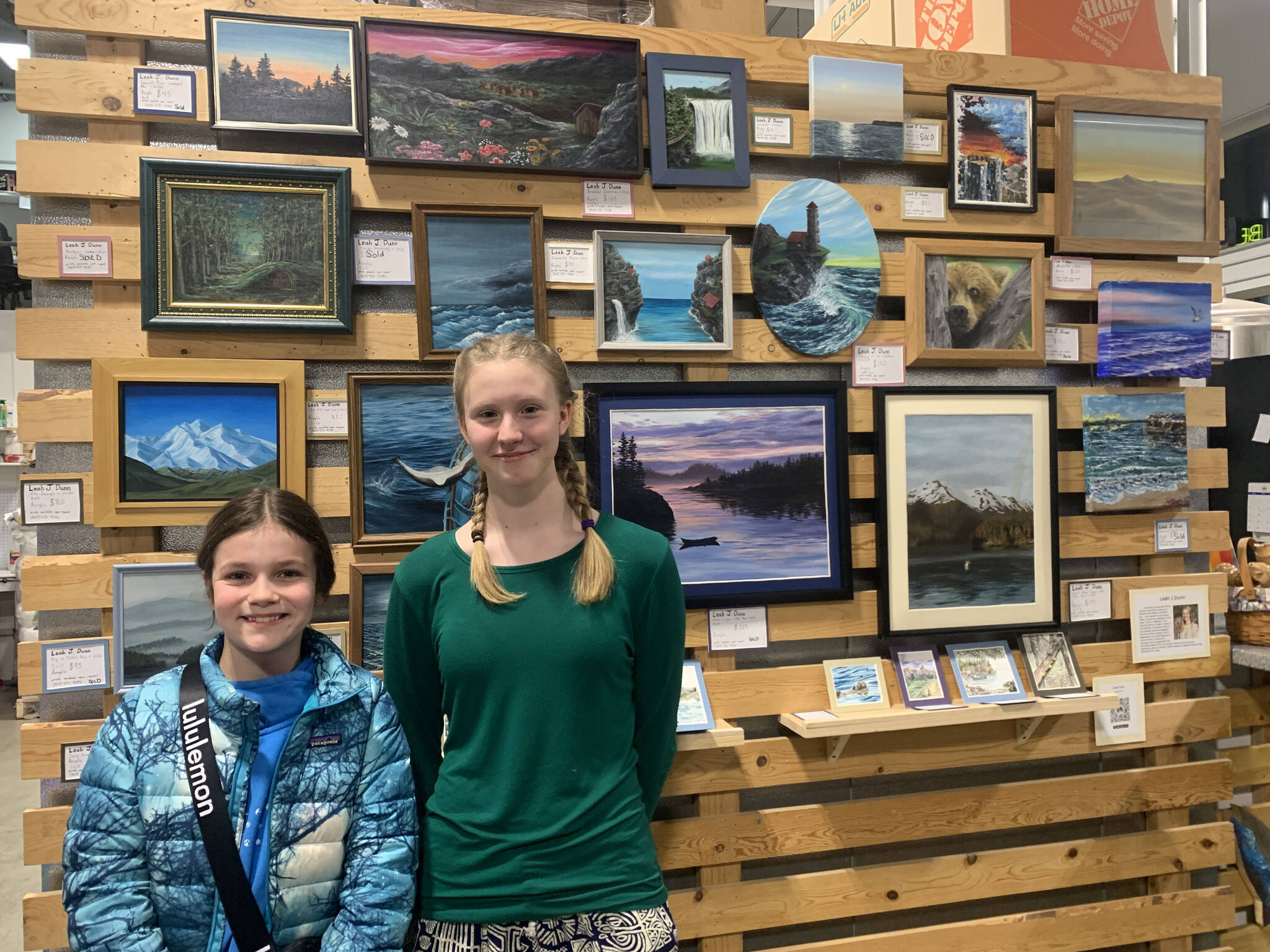 Homer youth artist Leah Dunn, right, and her friend Kyla Palin stand in front of Dunn’s exhibit during First Friday, on display at Grace Ridge Brewing through January. (Photo by Christina Whiting/Homer News)
