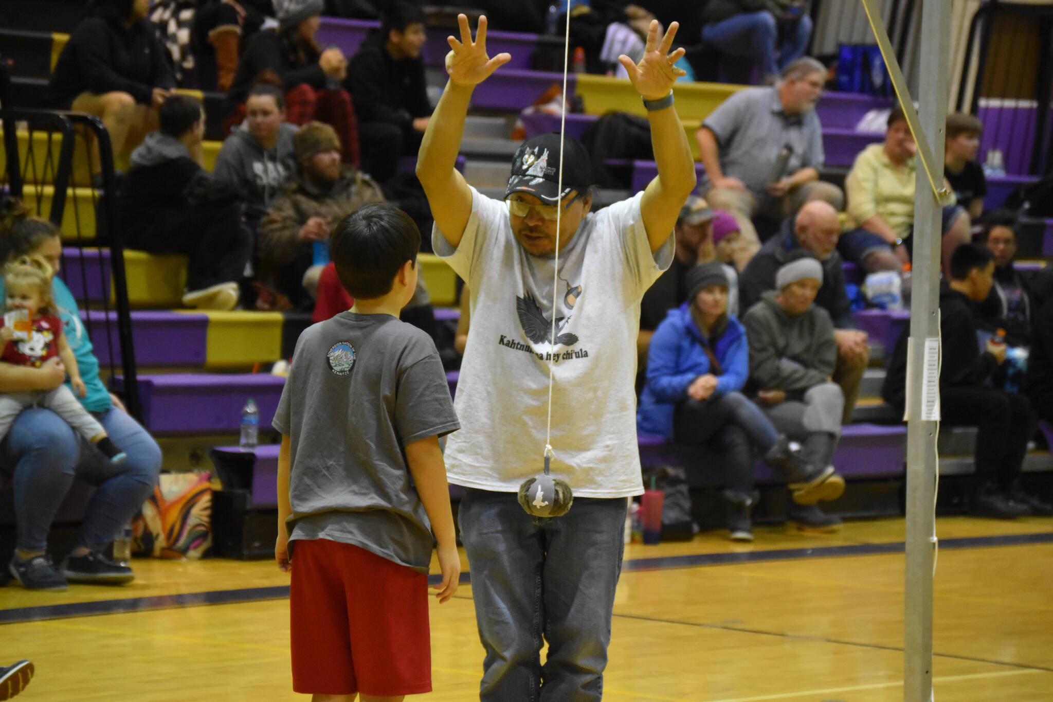 An official gives advice to a junior athlete competing for the Kenaitze Indian Tribe after the boy missed his first attempt at the 2-foot high kick during the Kahtnuht’ana Hey Chi’ula NYO Invitational on Saturday, Jan. 14, 2023, at Kenai Middle School in Kenai, Alaska. (Jake Dye/Peninsula Clarion)