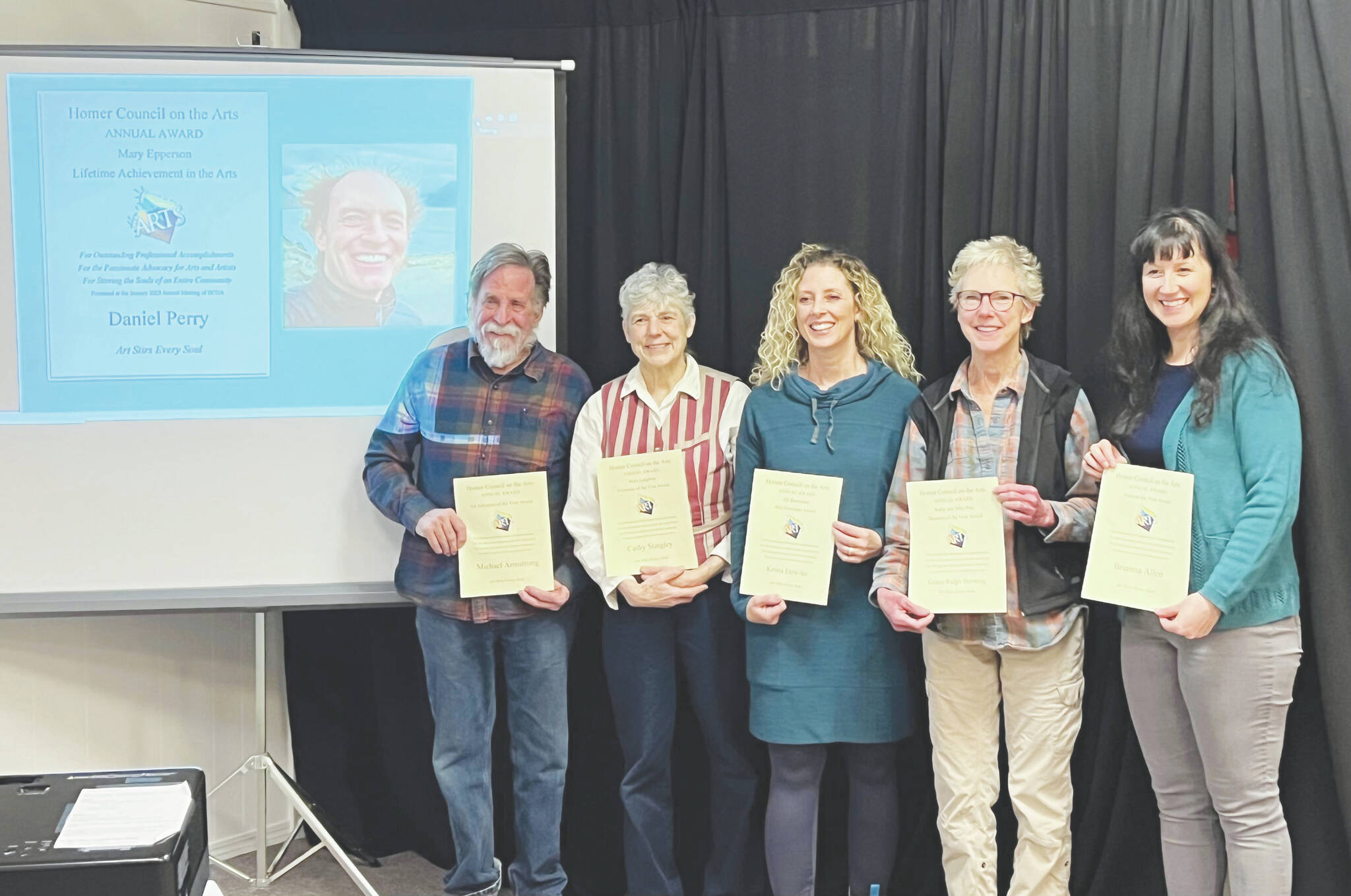 (from left to right) HCOA Community Arts Awardees Daniel Perry (pictured on screen), Michael Armstrong, Cathy Stingley, Krista Etzweiler, Sherry Stead and Brianna Allen pose with their awards at the HCOA annual meeting Friday.