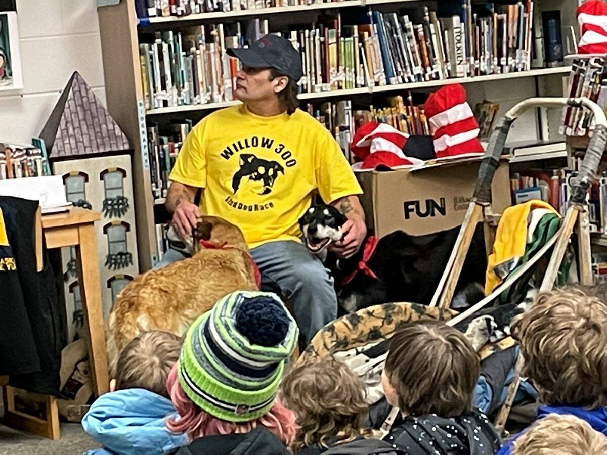 Musher Hugh Neff sits with his two retired sled dogs, Mojito (left) and Havana (right), at a presentation on reading and dog sledding at West Homer Elementary on Friday, Feb. 3 in Homer, Alaska. Photo courtesy of Barb Angaiak